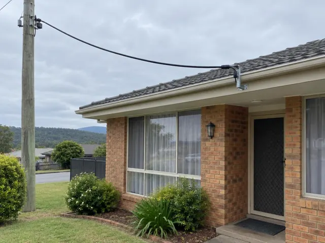 Overhead service cable and point-of-attachment bracket on a brick home exterior in Morisset